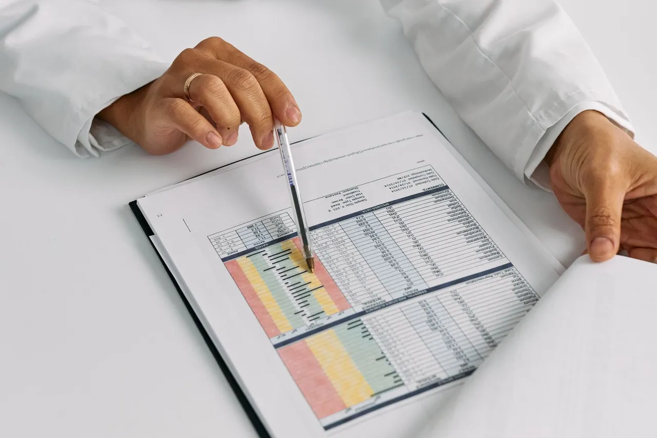 Manos de un médico revisando tablas de resultados con un bolígrafo
