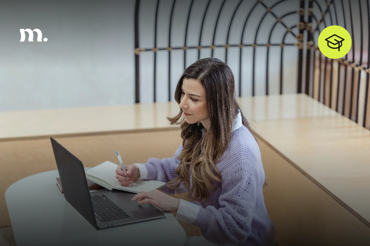 Mujer estudiando con una laptop y un cuaderno en un espacio de trabajo luminoso