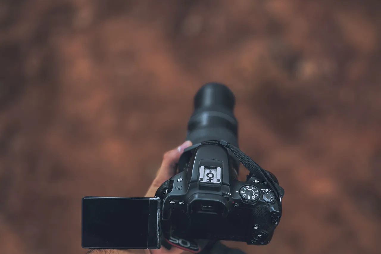 Fotógrafo sosteniendo una cámara réflex en exteriores