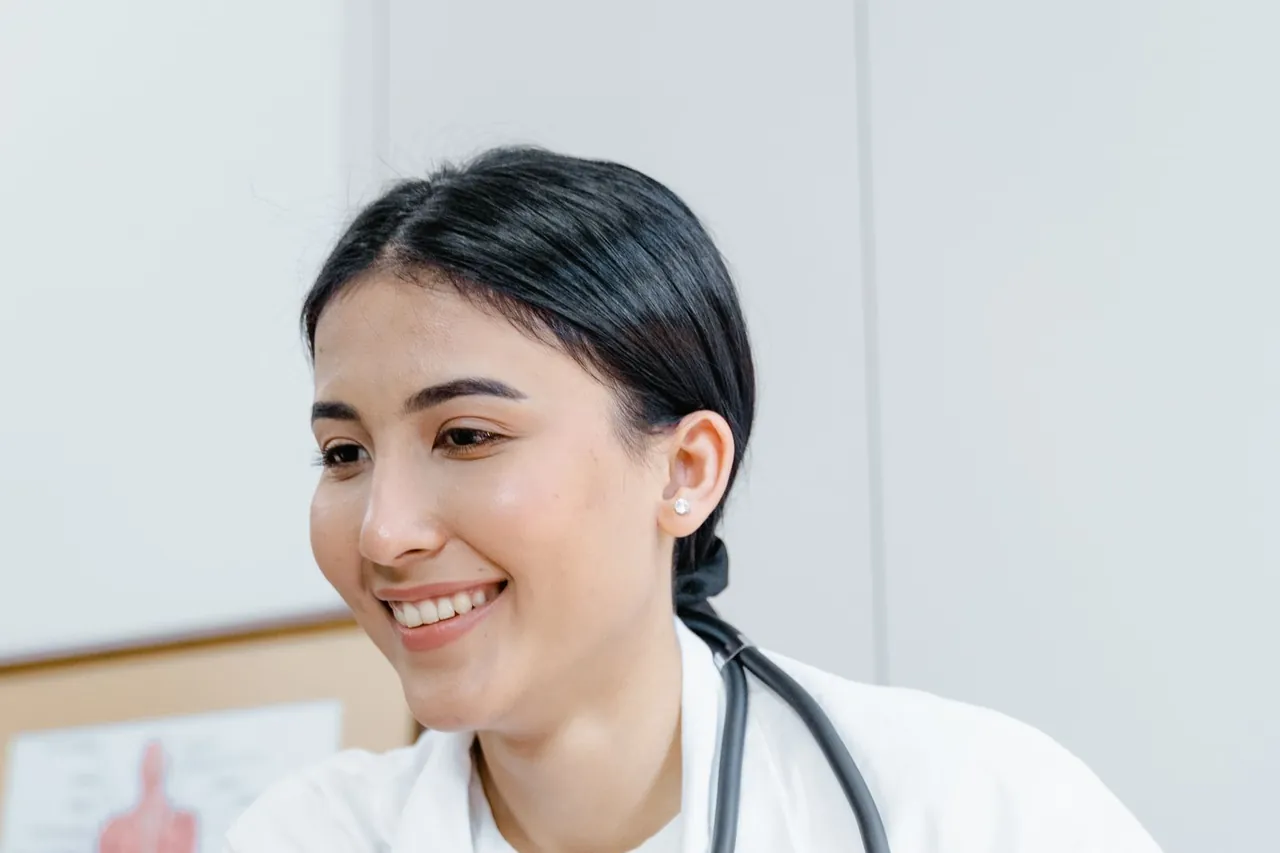 Doctora joven sonriendo con estetoscopio en una clínica