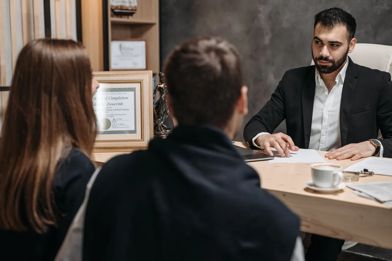 Abogado revisando documentos con dos clientes en su despacho