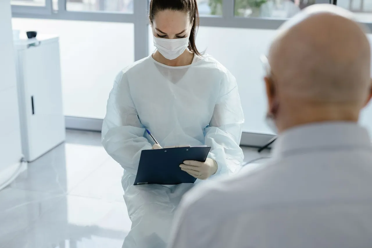 Médica con mascarilla atendiendo a un paciente en consulta