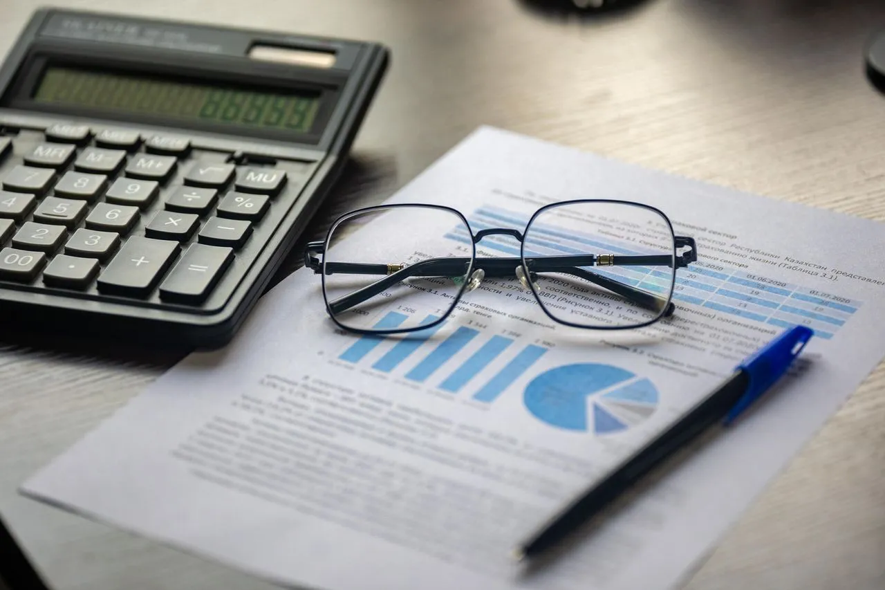 Calculadora, gafas y un informe con gráficos sobre un escritorio