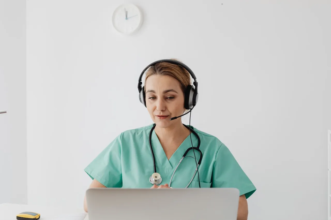 Enfermera con auriculares atendiendo una teleconsulta desde su laptop